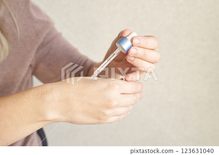 Young caucasian female applying skincare serum with dropper on hand Young caucasian female applying skincare serum with dropper on hand 123631040