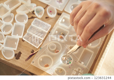Close up of hand working with resin molds and small objects for jewelry crafting 123631244
