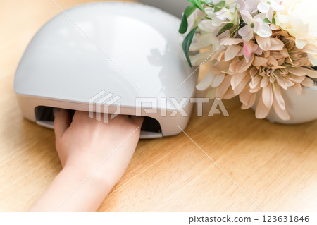 Woman curing gel nails with a nail light (nail machine, nail salon, self-nail) Woman curing gel nails with a nail light (nail machine, nail salon, self-nail) 123631846