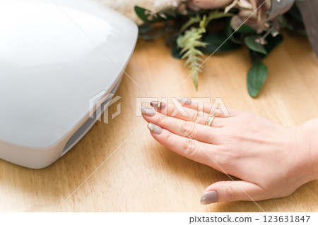 Woman curing gel nails with a nail light (nail machine, nail salon, self-nail) Woman curing gel nails with a nail light (nail machine, nail salon, self-nail) 123631847