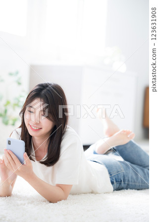 廣角鏡頭下,一位身穿春夏短袖的年輕女子趴在房間裡,敲打著智慧型手機 廣角鏡頭下,一位身穿春夏短袖的年輕女子趴在房間裡,敲打著智慧型手機 123631908