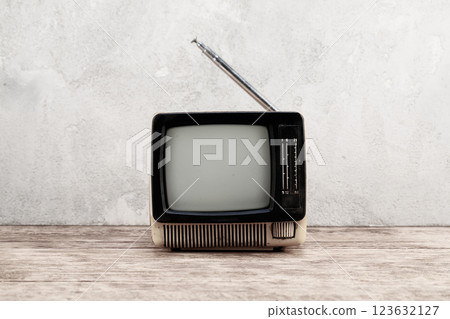 Old vintage retro analog TV set stand on wooden floor front aged concrete wall background. Old vintage retro analog TV set stand on wooden floor front aged concrete wall background. 123632127