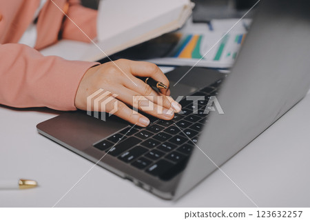 Cropped image of professional businesswoman working at her office via laptop, young female manager using portable computer device while sitting at modern loft, flare light, work process concept 123632257