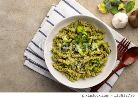 Vegetarian vegan green pasta, small spiral pasta with broccoli pesto sauce and vegan cheese in white plate.Healthy food.Top view. 123632756