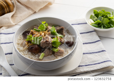 Pork Porridge.Boiled rice with Pork Baby Back Ribs or pork cartilage with shitake mushroom in white bowl.Asian breakfast style 123632758
