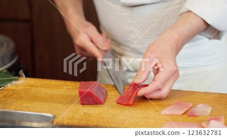 The hands of a sushi chef cutting red tuna 123632781