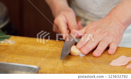 The hands of a sushi chef cutting scallops The hands of a sushi chef cutting scallops 123632782