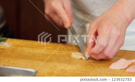 The hands of a sushi chef cutting scallops 123632783