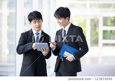 Business: Young male employees consulting in the hallway 123633040