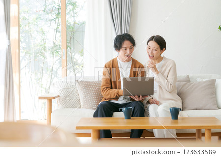 A couple sitting on a sofa looking at a computer A couple sitting on a sofa looking at a computer 123633589