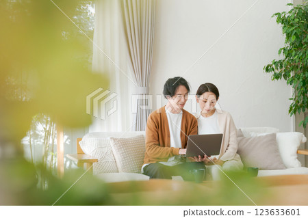 A couple sitting on a sofa looking at a computer A couple sitting on a sofa looking at a computer 123633601