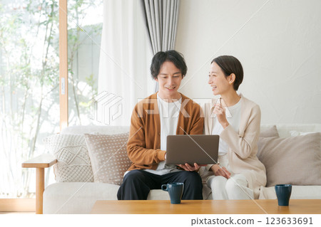 A couple looking at a personal computer in the living room 123633691
