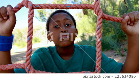 Tired boy leaning on net during obstacle course in boot camp 123634080