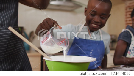 African american father and son wearing aprons baking together in the kitchen at home 123634092