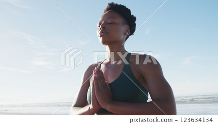 African american woman meditating at the beach on sunny day African american woman meditating at the beach on sunny day 123634134