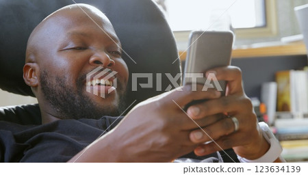 Front view of African american man using mobile phone in a comfortable home 123634139