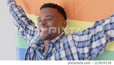 Happy african american man holding lgbt rainbow flag and smiling, slow motion Happy african american man holding lgbt rainbow flag and smiling, slow motion 123634158