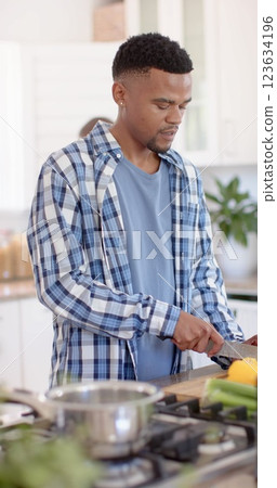 Vertical image of african american man chopping vegetables in kitchen Vertical image of african american man chopping vegetables in kitchen 123634196