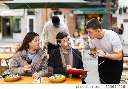 Couple husband and wife ordering from boyfriend waiter in restaurant 123634226