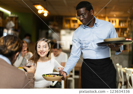 African waiter with tray in hands bringing food 123634336