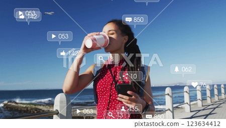 Drinking coffee and holding smartphone, woman with social media notifications image 123634412