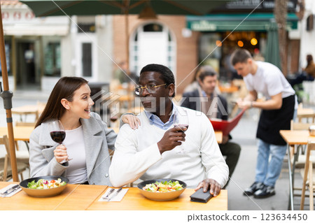 Interethnic couple happily chatting while sitting on the terrace of a restaurant 123634450