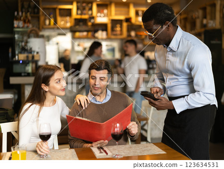 African man listen to restaurant couple customer, writes down order African man listen to restaurant couple customer, writes down order 123634531
