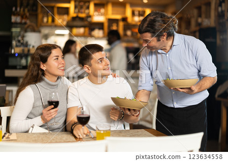 Male waiter brings dishes that the couple ordered 123634558