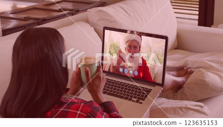 Image of snow falling over biracial woman on laptop image call with santa at christmas Image of snow falling over biracial woman on laptop image call with santa at christmas 123635153