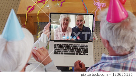 Merry christmas text over senior couple having a imagecall on laptop during christmas 123635155