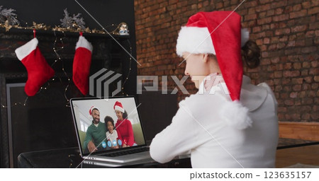 Image of snow falling over caucasian girl in santa hat on laptop image call at christmas 123635157