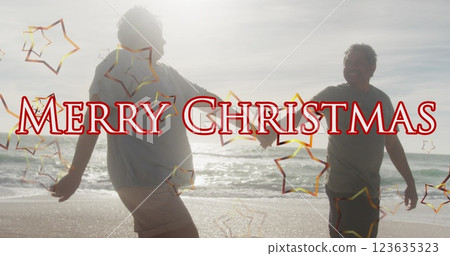 Image of merry christmas text over senior biracial couple at beach Image of merry christmas text over senior biracial couple at beach 123635323