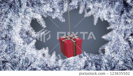 Image of hanging gift box swinging over snow covered pine leaves against gray background 123635502