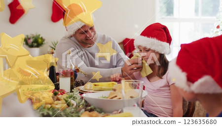 Caucasian father and daughter wearing festive hats, enjoying Christmas dinner 123635680