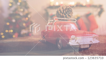 Red toy car carrying pine cone on roof, parking near Christmas tree Red toy car carrying pine cone on roof, parking near Christmas tree 123635710
