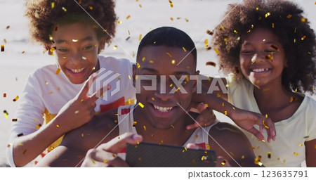 Image of christmas confetti over african american family taking selfie on beach 123635791