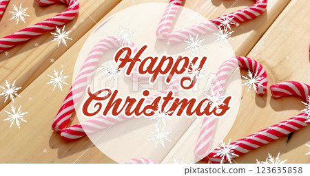 Image of christmas greetings text over christmas candy canes decorations and snow 123635858