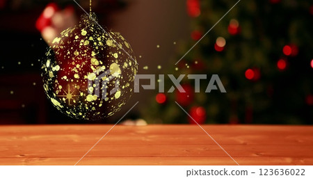 Image of gold christmas bauble swinging over defocussed flashing fairy lights on tree 123636022