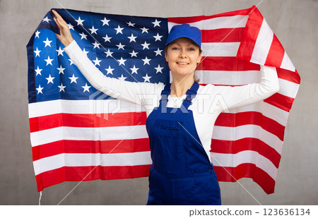 Cheerful female worker with wide grin on her face holding flag of usa Cheerful female worker with wide grin on her face holding flag of usa 123636134