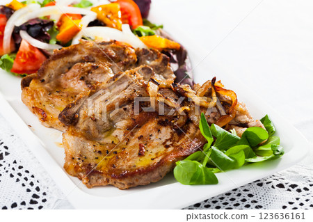 Cooked fried pork chops with salad of fried orange, lettuche and tomatoes Cooked fried pork chops with salad of fried orange, lettuche and tomatoes 123636161
