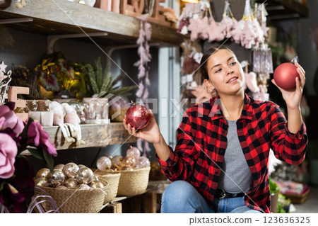 Cheerful girl selecting baubles in store Cheerful girl selecting baubles in store 123636325