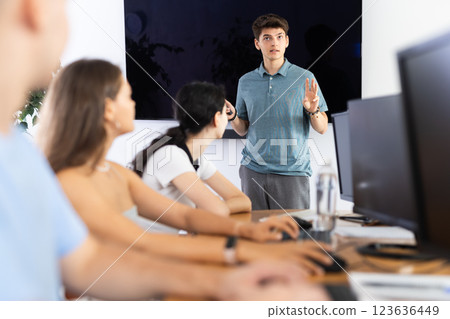 Young guy speaker stands in front of students and talks about use of artificial intelligence Young guy speaker stands in front of students and talks about use of artificial intelligence 123636449