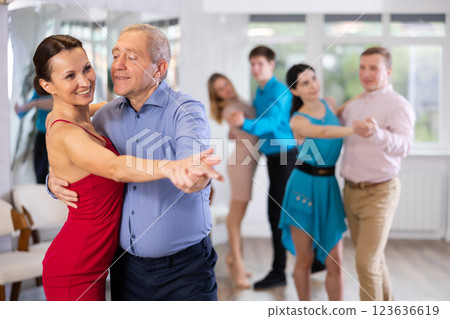 Elderly man enjoying slow foxtrot with female partner in dance studio 123636619
