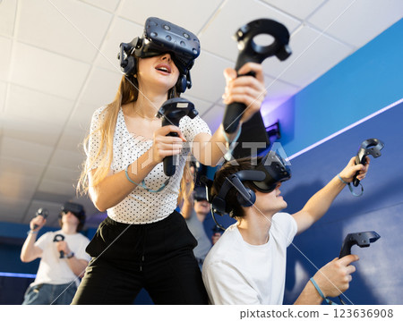 Young woman in virtual glasses plays virtual reality games with friends in special room 123636908