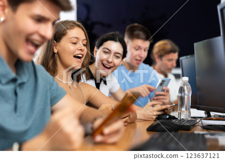 At computer class, young girl student sits with mobile phone and listens admiringly to teacher At computer class, young girl student sits with mobile phone and listens admiringly to teacher 123637121