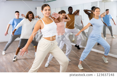 Class of active young adult dancers performing steps during exercising modern dance together in dance hall 123637148