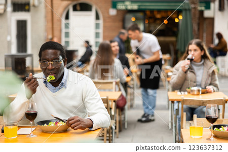 On open area of cafe, African man in restaurant eating salad 123637312