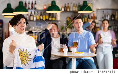 Sad girl with friends upset by the loss of her favorite team of Uruguay 123637314
