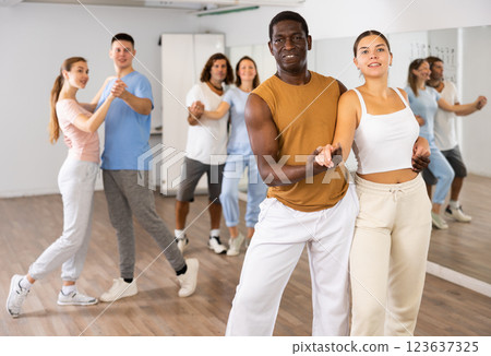 Group of joyful adult young diverse men and women learning new dancing in pairs during during learning new movements in studio 123637325