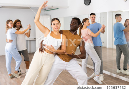 Joyful young adult couples learning passionate pair dancing during practicing in choreography class Joyful young adult couples learning passionate pair dancing during practicing in choreography class 123637382